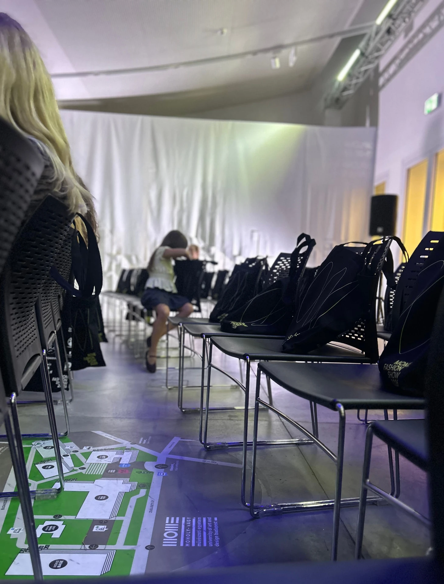 MOME Fashion Show 2026 - a nézőtér az esemény előtt, ajándéktáskák a székeken